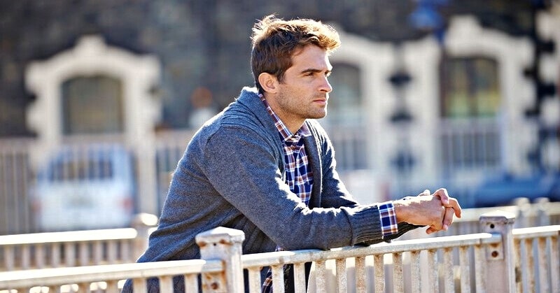pensive man looking out from bridge missing his old life
