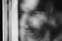 blurred image of man looking through window feeling passive suicidal ideation