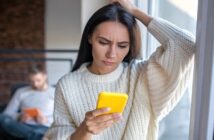 woman looking at her cell phone comparing herself to her boyfriend's ex