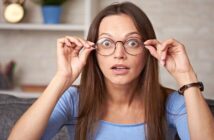 woman with surprised look on face adjusting her glasses