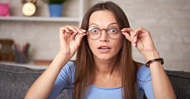 woman with surprised look on face adjusting her glasses