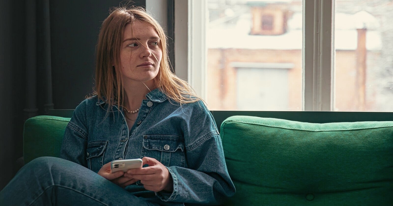 pensive young woman on couch because she hates socializing