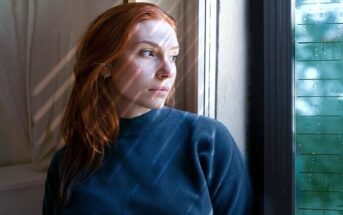 woman looking pensively out of window regretting missed opportunities