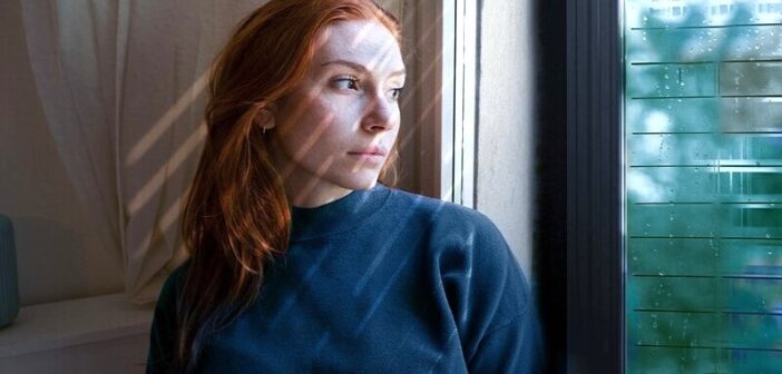 woman looking pensively out of window regretting missed opportunities
