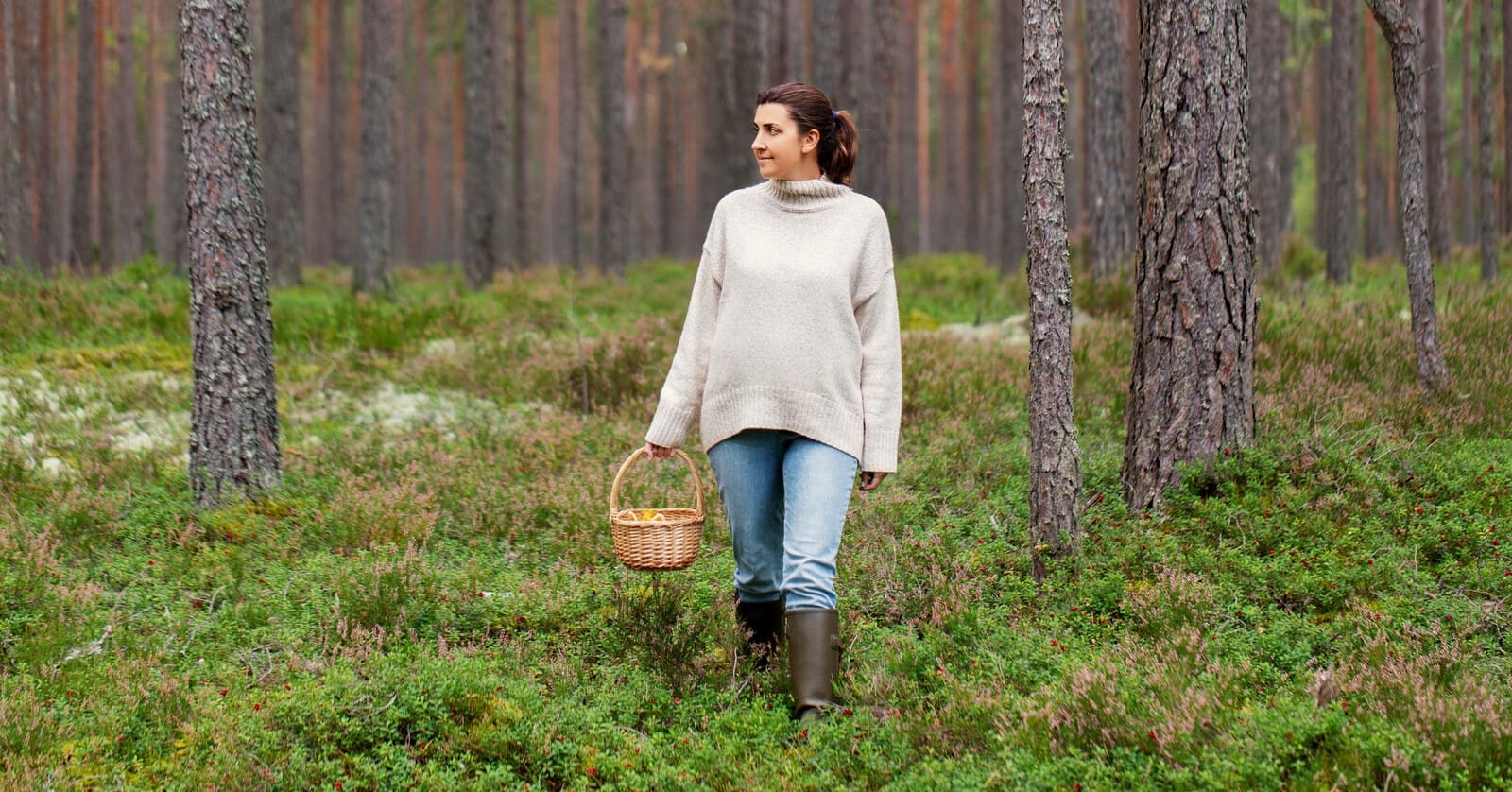 a down-to-earth woman walking through forest with a basket