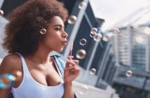woman blowing bubbles on street to illustrate letting go of things