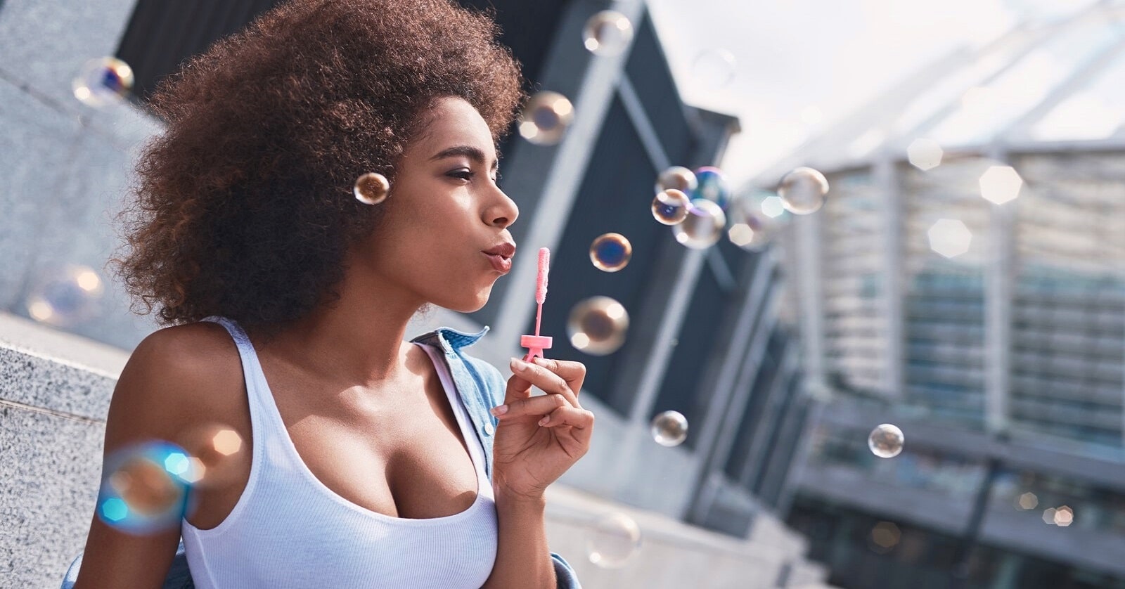 woman blowing bubbles on street to illustrate letting go of things