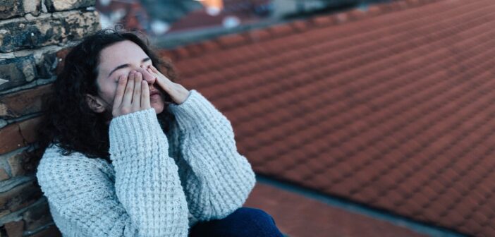 young woman on rooftop with her hands over her eyes