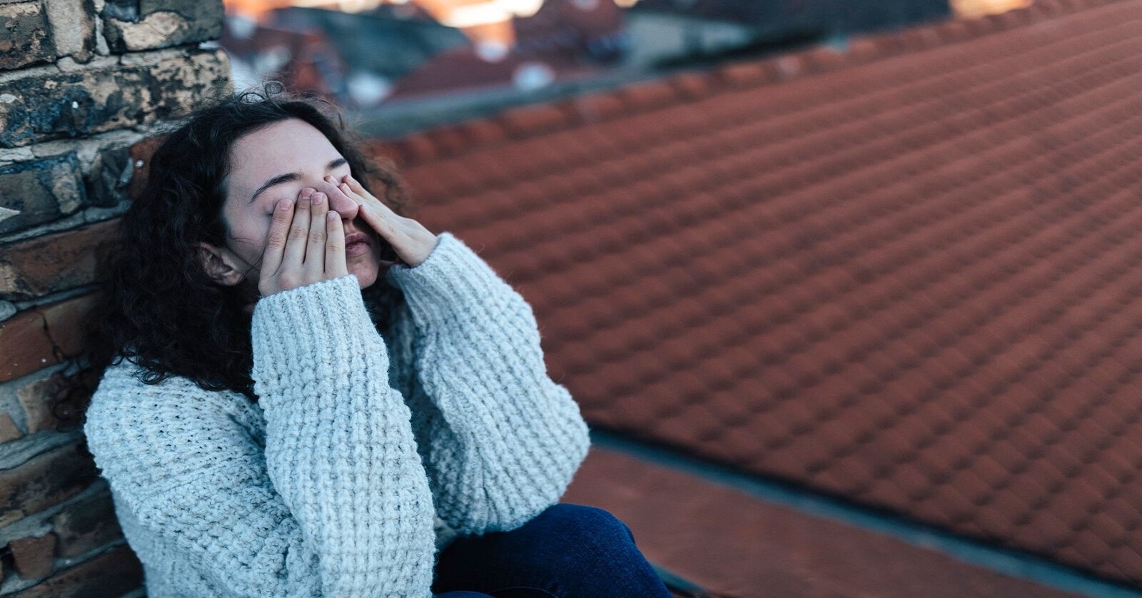 young woman on rooftop with her hands over her eyes