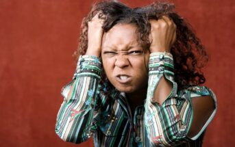 woman grasping her hair in anger over something small