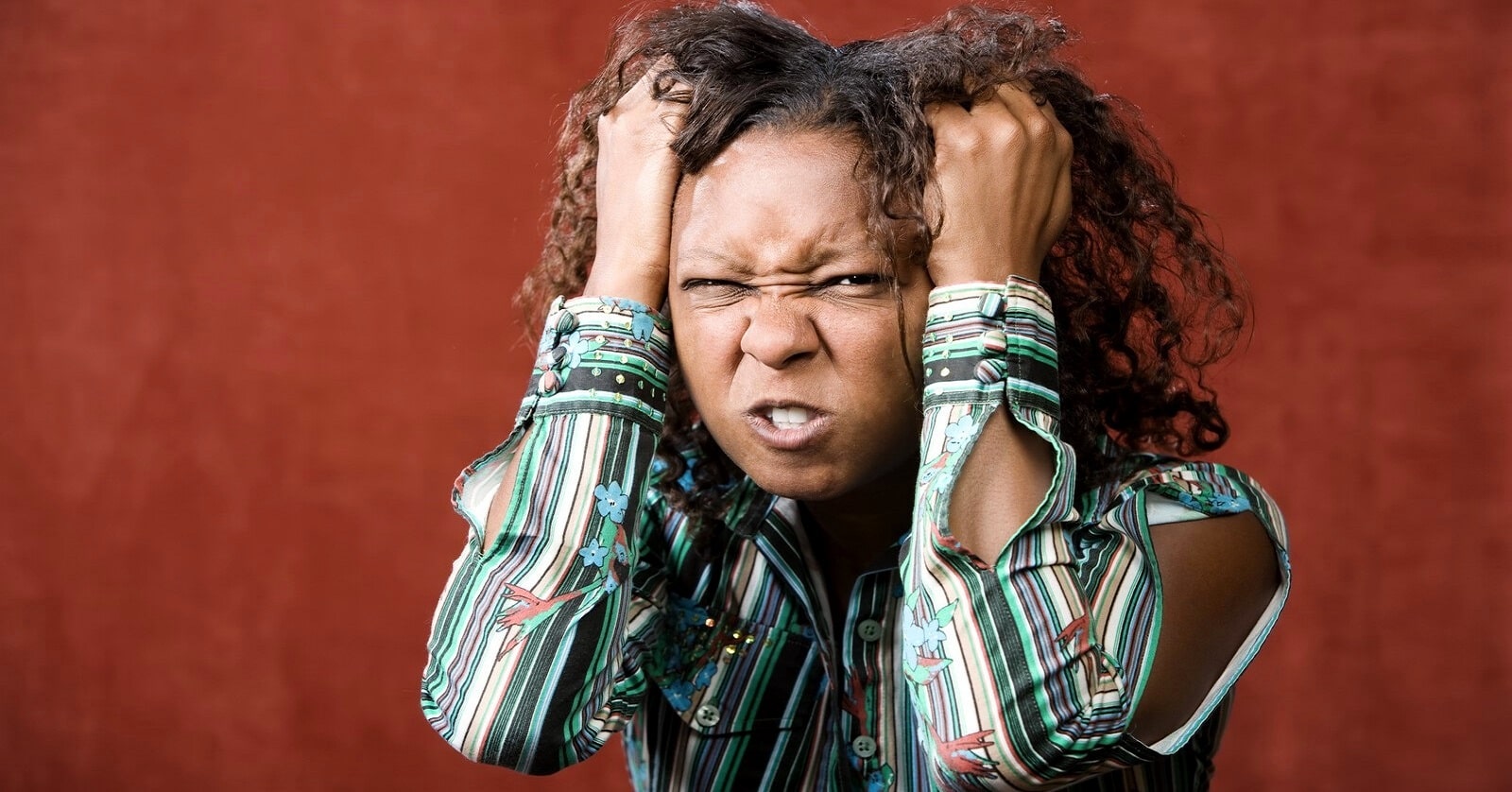 woman grasping her hair in anger over something small