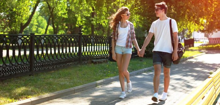 young girl and guy holding hands walking in the park on a date