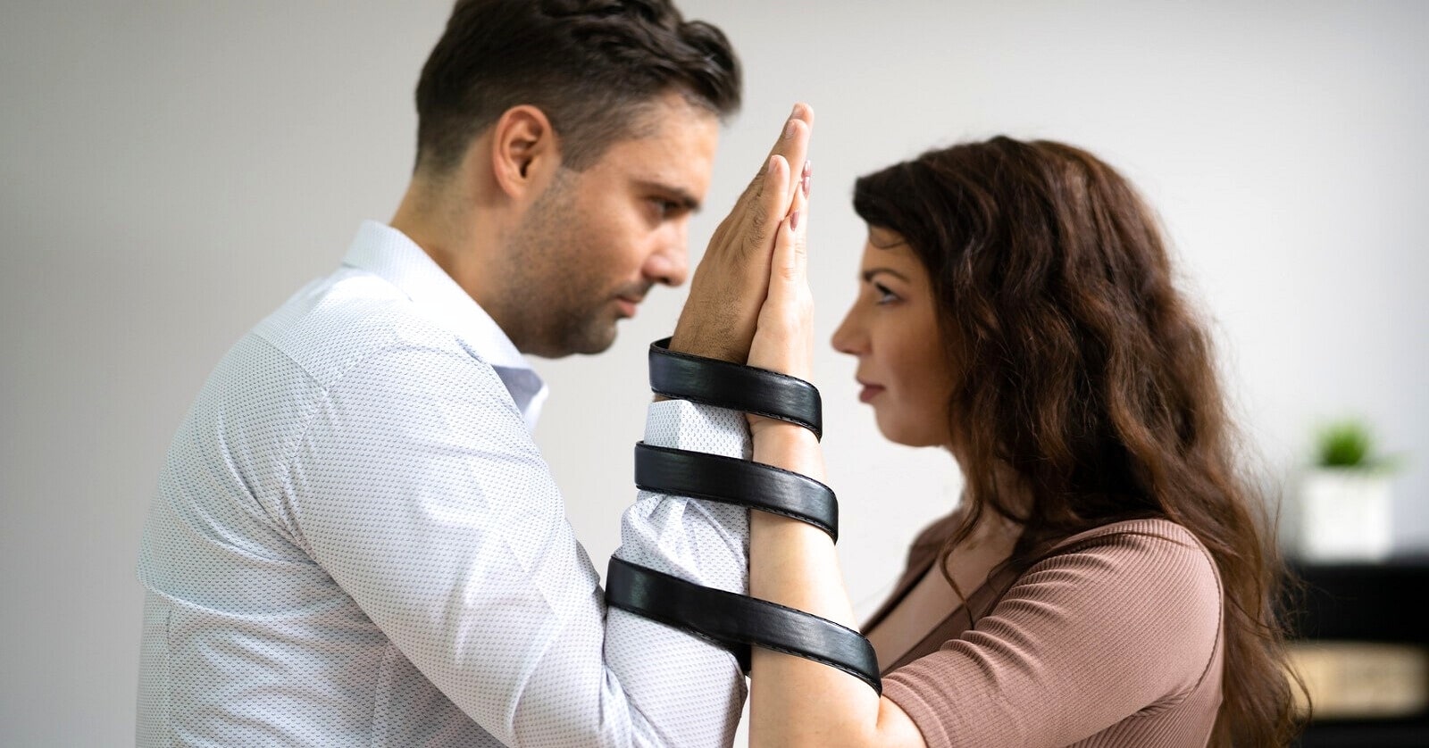 man and woman bound together by leather belt around their arms