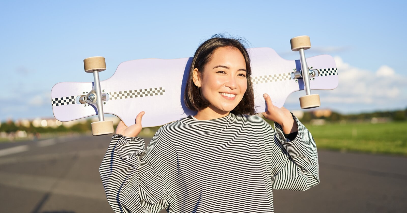 young smiling woman carrying a skateboard