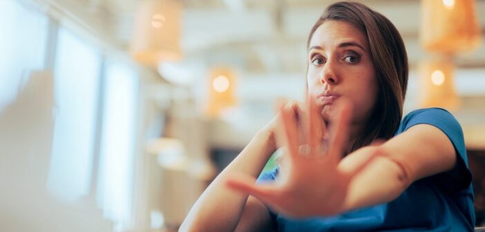 woman with outstretched hand with palm facing the camera indicating that she doesn't want to deal with you
