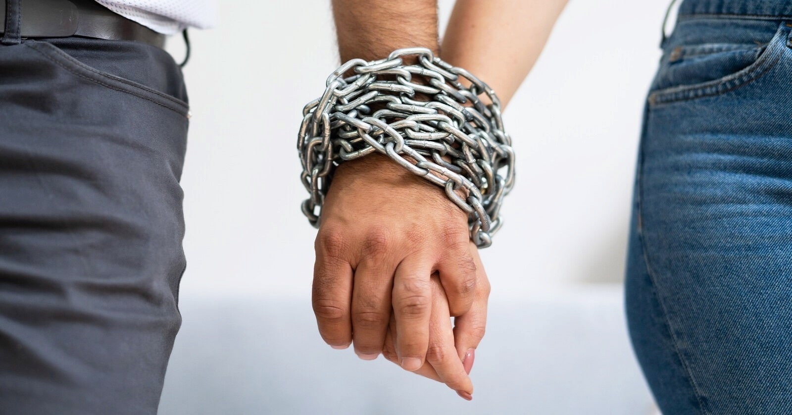 man and woman holding hands with a chain around their hands to illustrate a narcissistic relationship