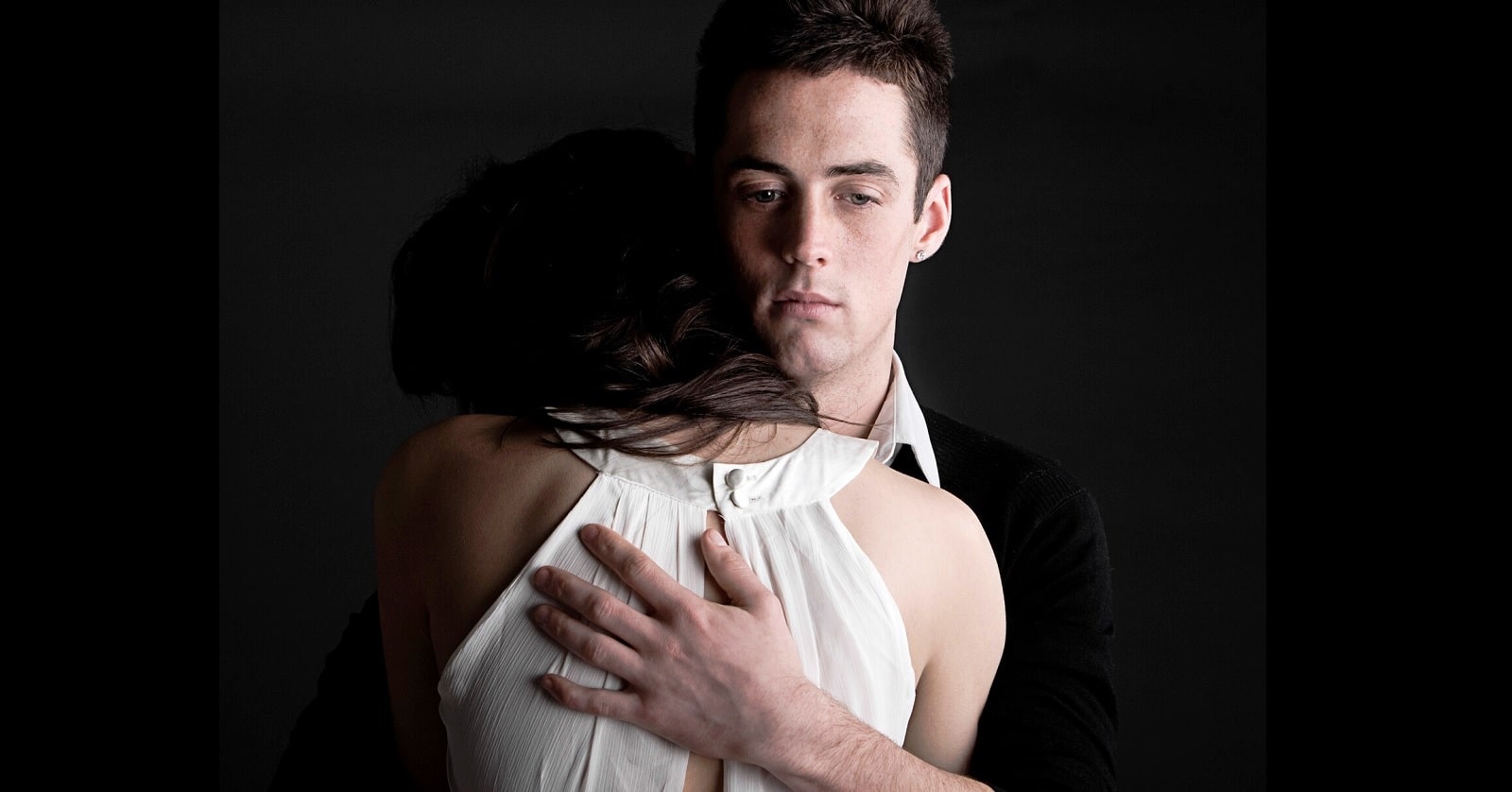 man facing camera hugging his girlfriend who is facing away from camera - illustrating an obsessive boyfriend