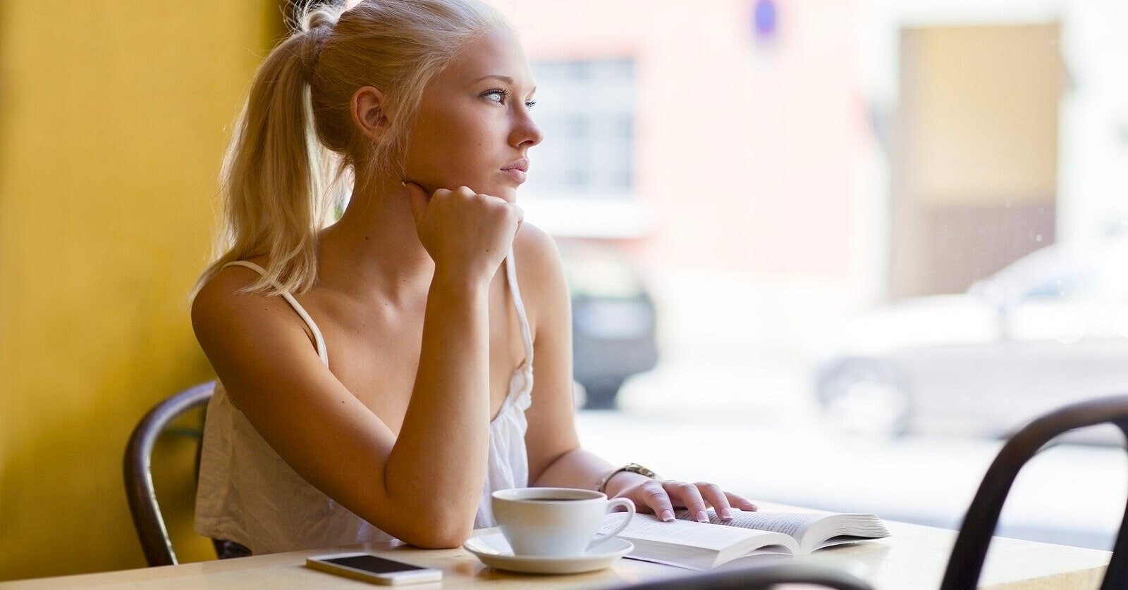 pensive woman in coffee shop looking out of the window