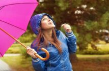 young woman with blue coat holding a pink umbrella