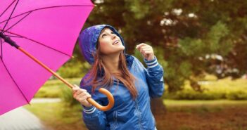 young woman with blue coat holding a pink umbrella