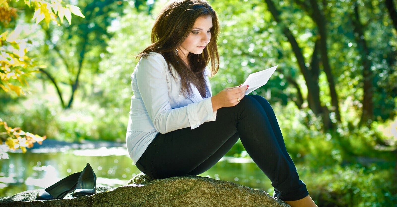 young woman reading a letter in a forest setting
