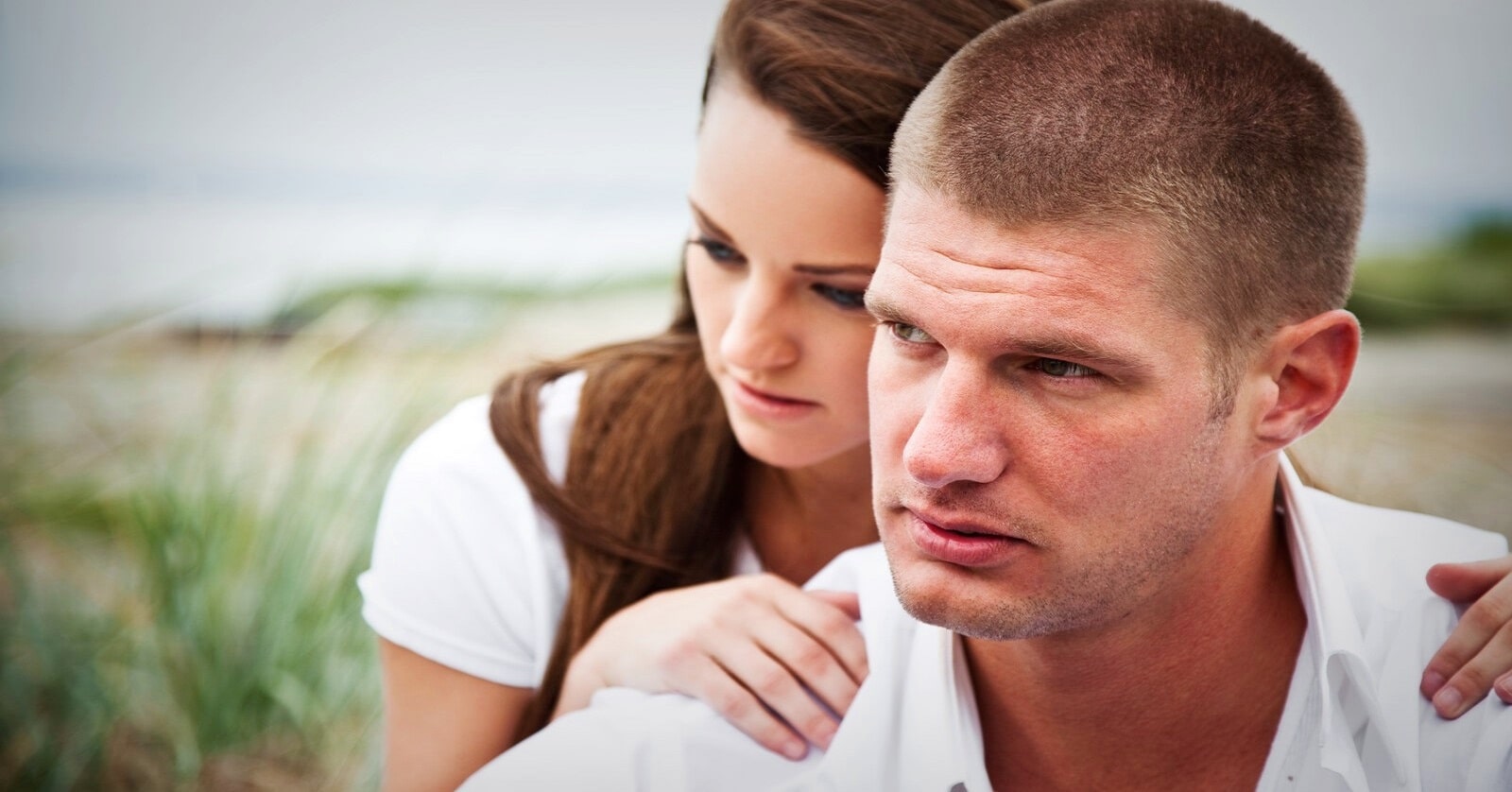 woman behind man with hands on his shoulders - illustrating loving someone who hurt you