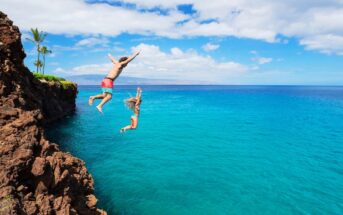 two young people taking a risk by jumping from cliffs into the ocean