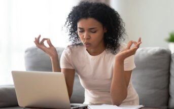 woman doing breathing exercise while sitting in front of her laptop to illustrate being less emotionally reactive