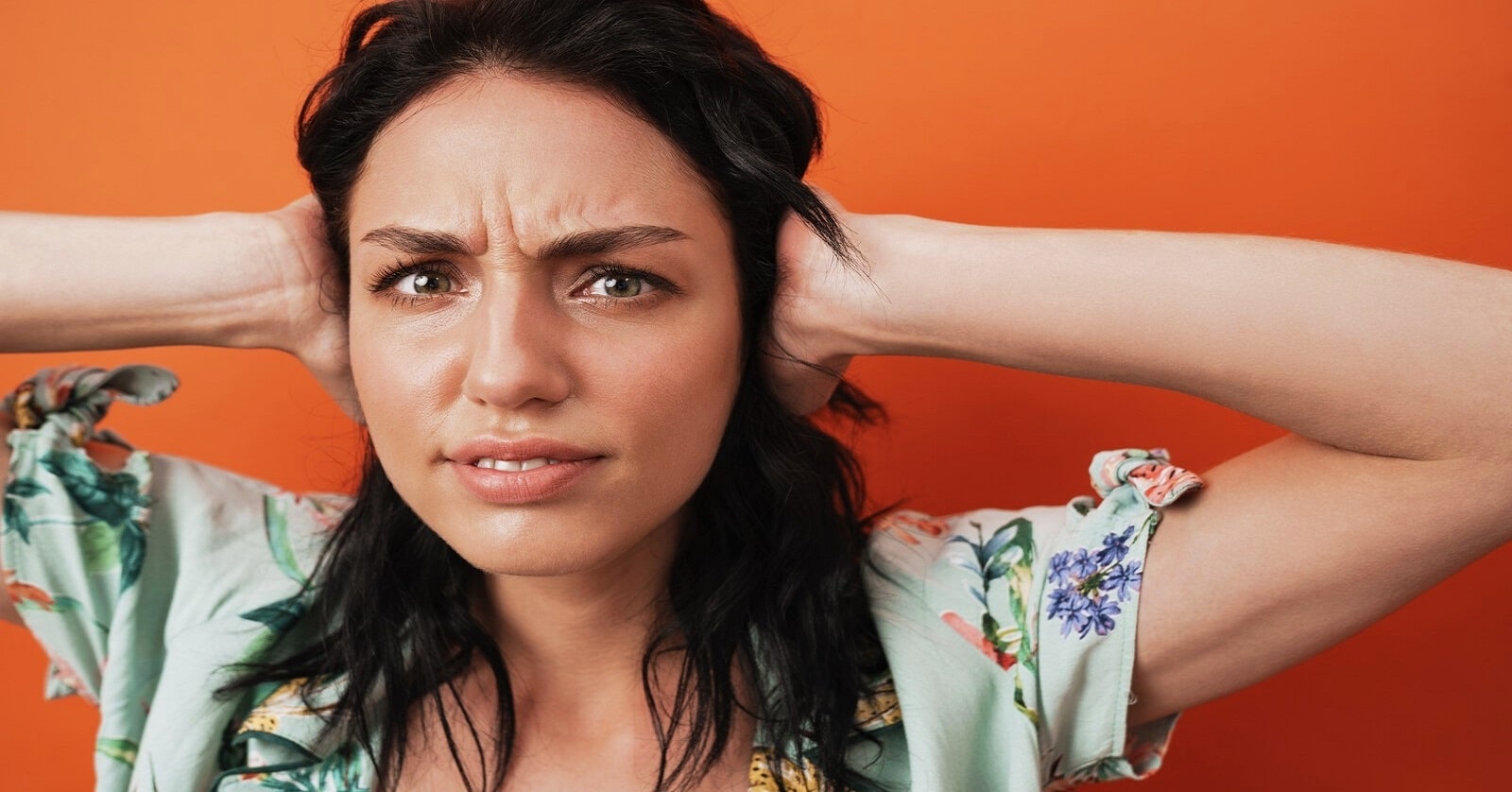 woman with hands over her ears because she's fed up of listening to someone complain