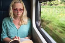 woman reading a book sitting by the window on a moving train