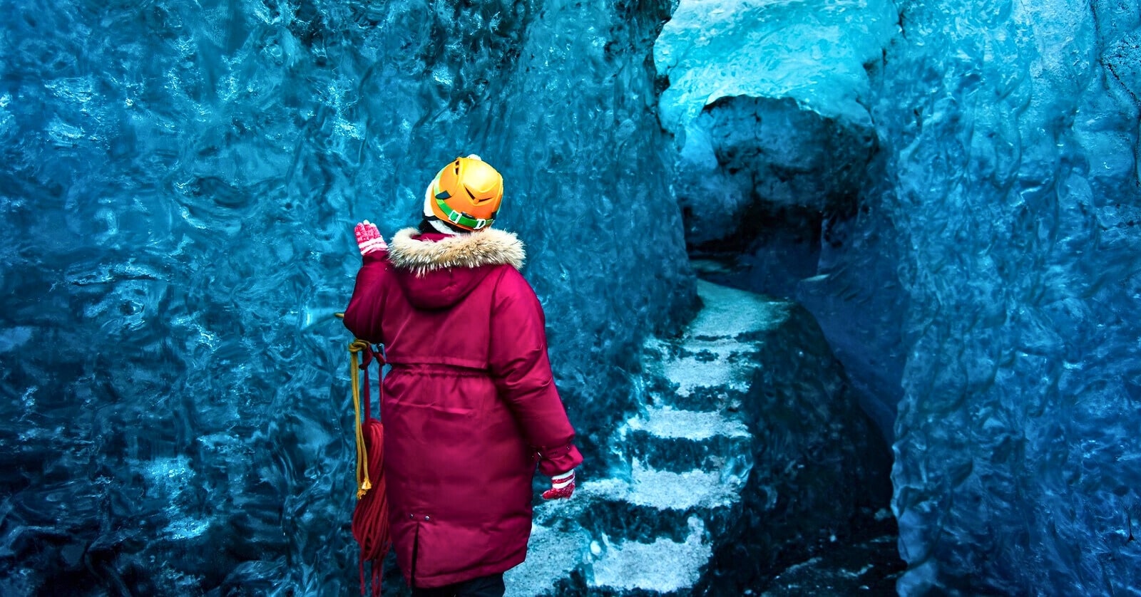 woman walking through a blue ice cave - illustrating the concept of perseverance