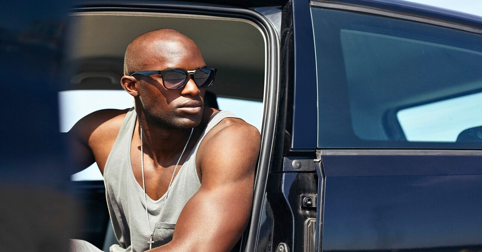 bald African American man sitting in his car with the door open - illustrating the idea of someone who commands respect from others