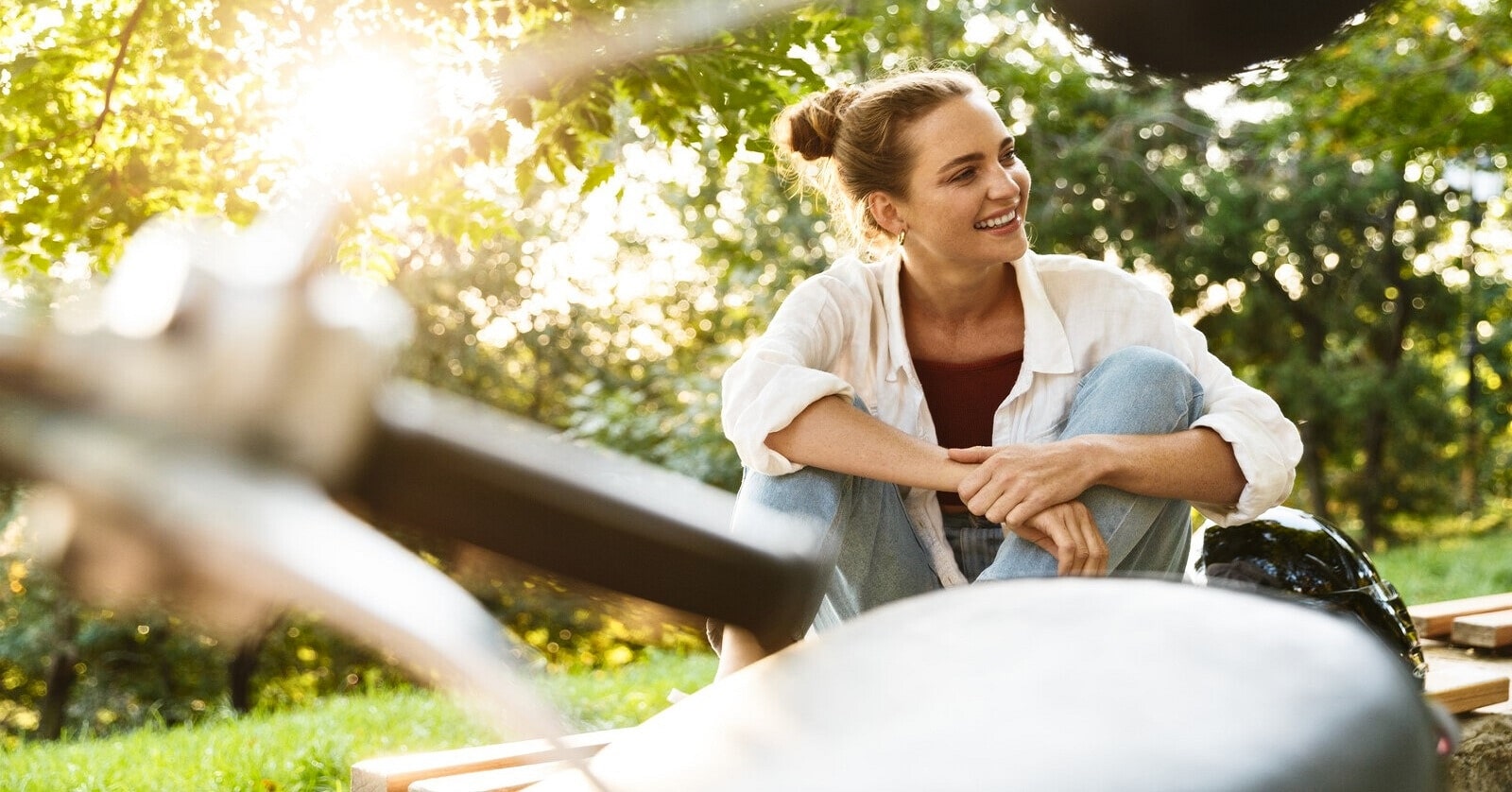 photo of a smiling confident woman with a motorbike seat and handlebars in the foreground