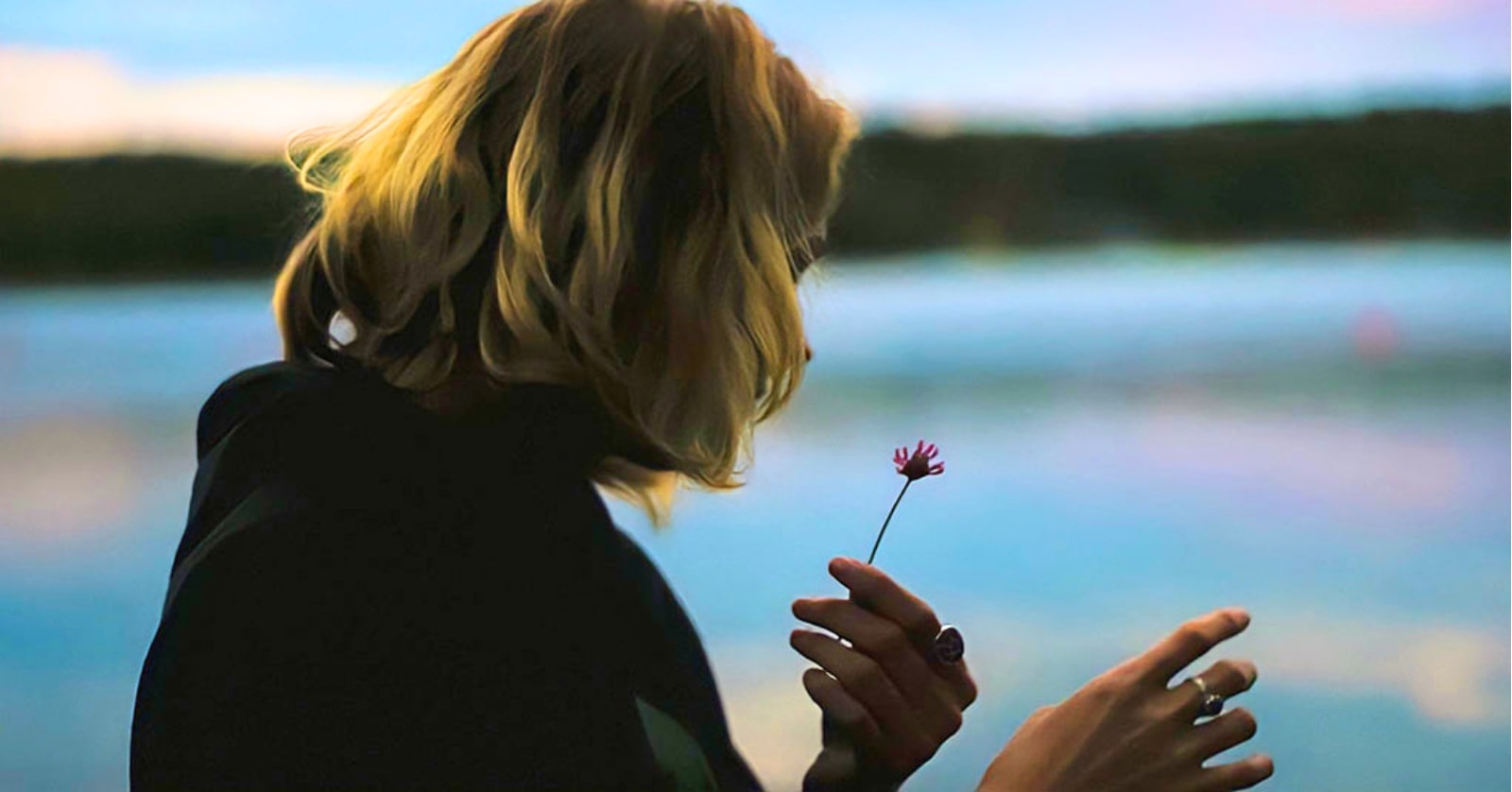 young woman picking petals from a flower to show she is a hopeless romantic