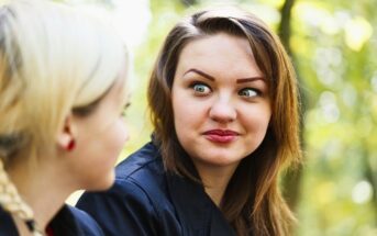 woman staring intensely at her friend with crazy eyes, making her friend uncomfortable