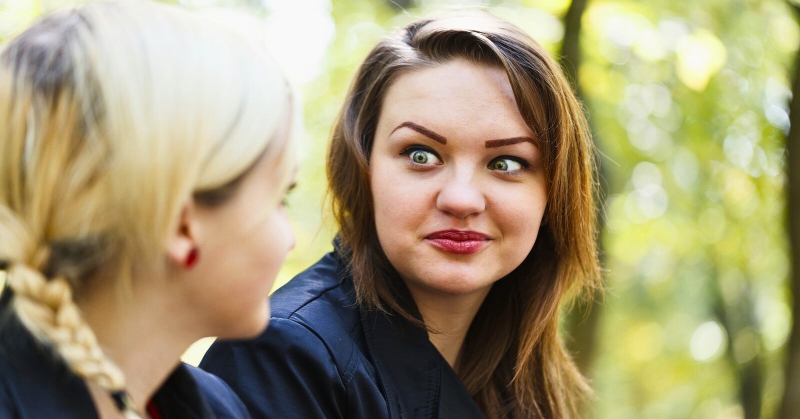 woman staring intensely at her friend with crazy eyes, making her friend uncomfortable