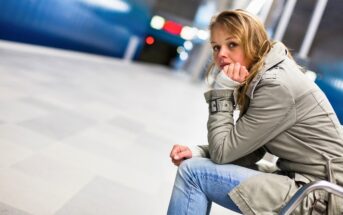 young woman in metro station wearing winter coat with a distant but pained expression on her face