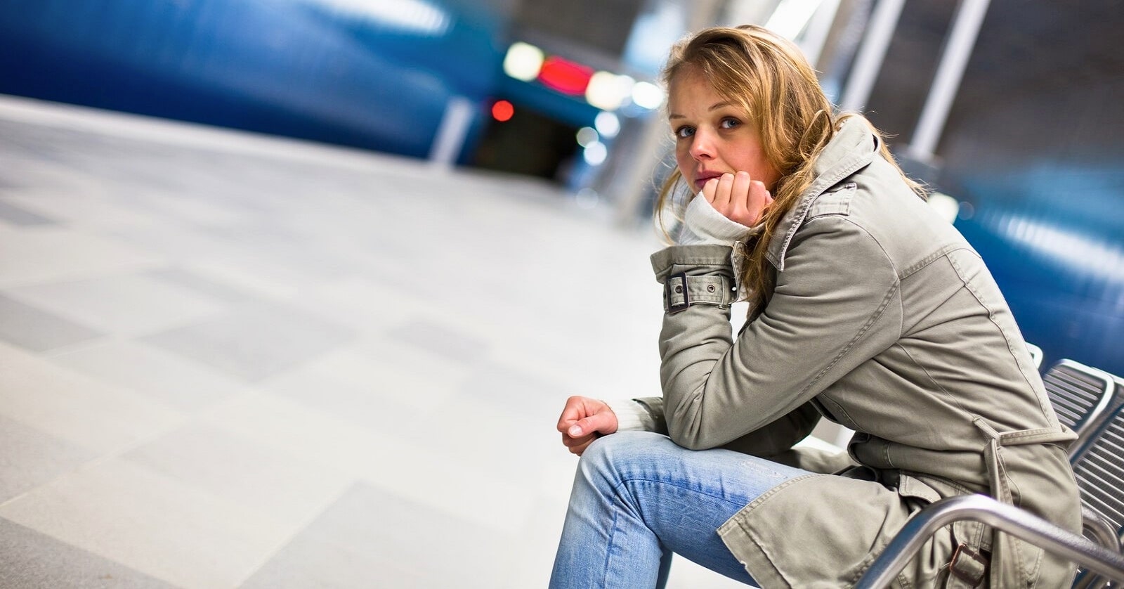 young woman in metro station wearing winter coat with a distant but pained expression on her face