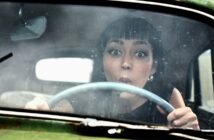 young brunette woman with funny look on her face sitting in a vintage but rusting old car