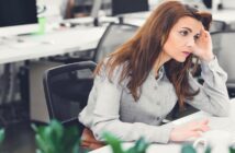 woman who has creative personality looking bored stuck at her desk in a bland open plan office