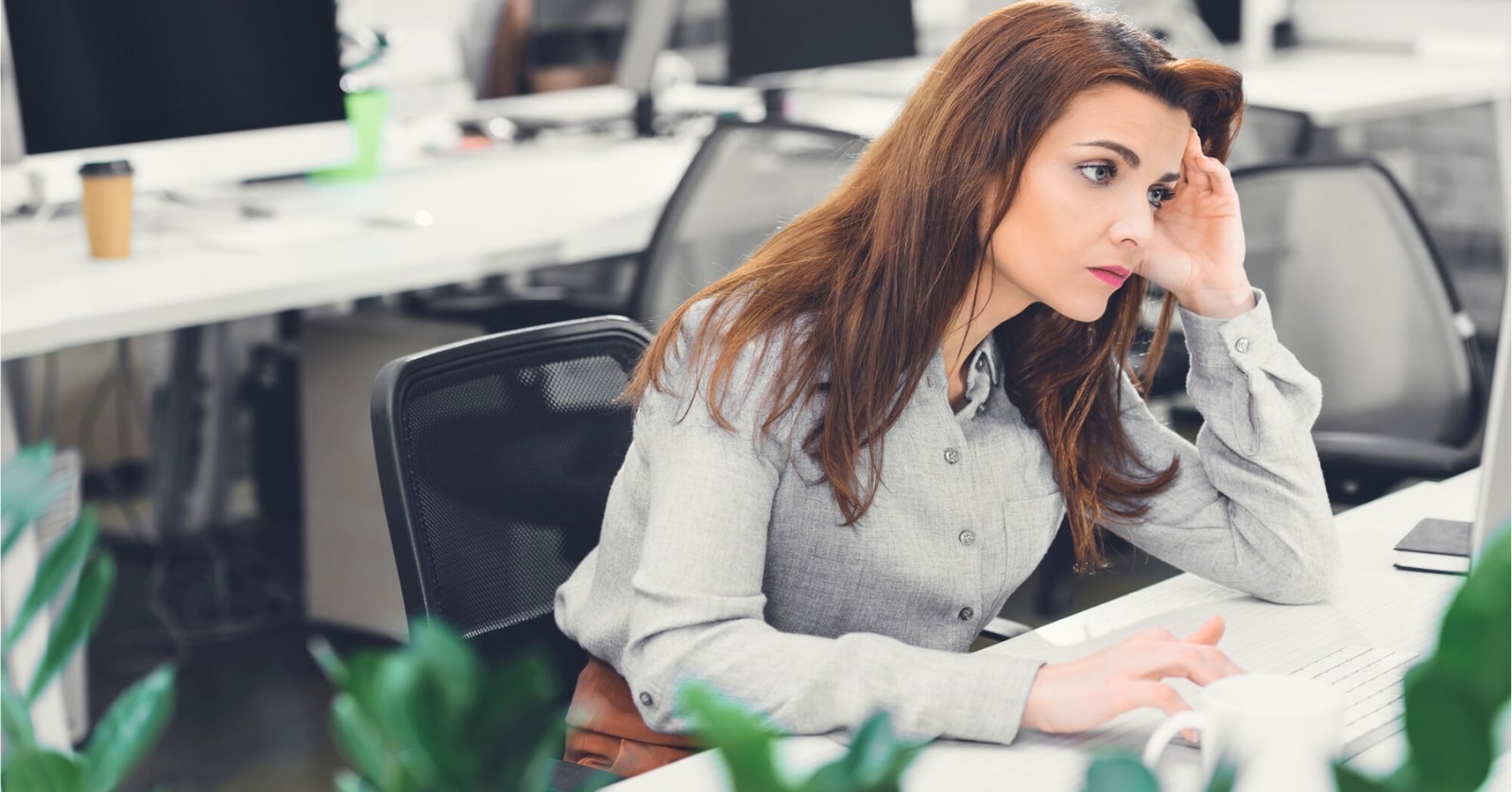 woman who has creative personality looking bored stuck at her desk in a bland open plan office