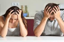 couple sitting a kitchen counter, both with their head in their hands because the relationship is not good
