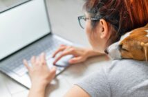 10 habits all hard-working individuals have in common (that many people lack) young woman with red hair laying on floor working on her laptop while her small dog sits on her back
