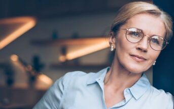 pensive middle-aged woman wearing smart blouse and glasses
