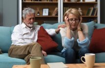 late middle aged couple looking unhappy sitting on the couch in their home after their children have moved out