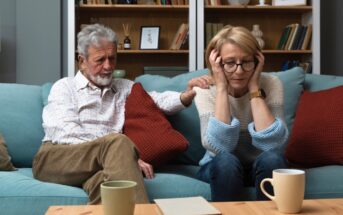 late middle aged couple looking unhappy sitting on the couch in their home after their children have moved out