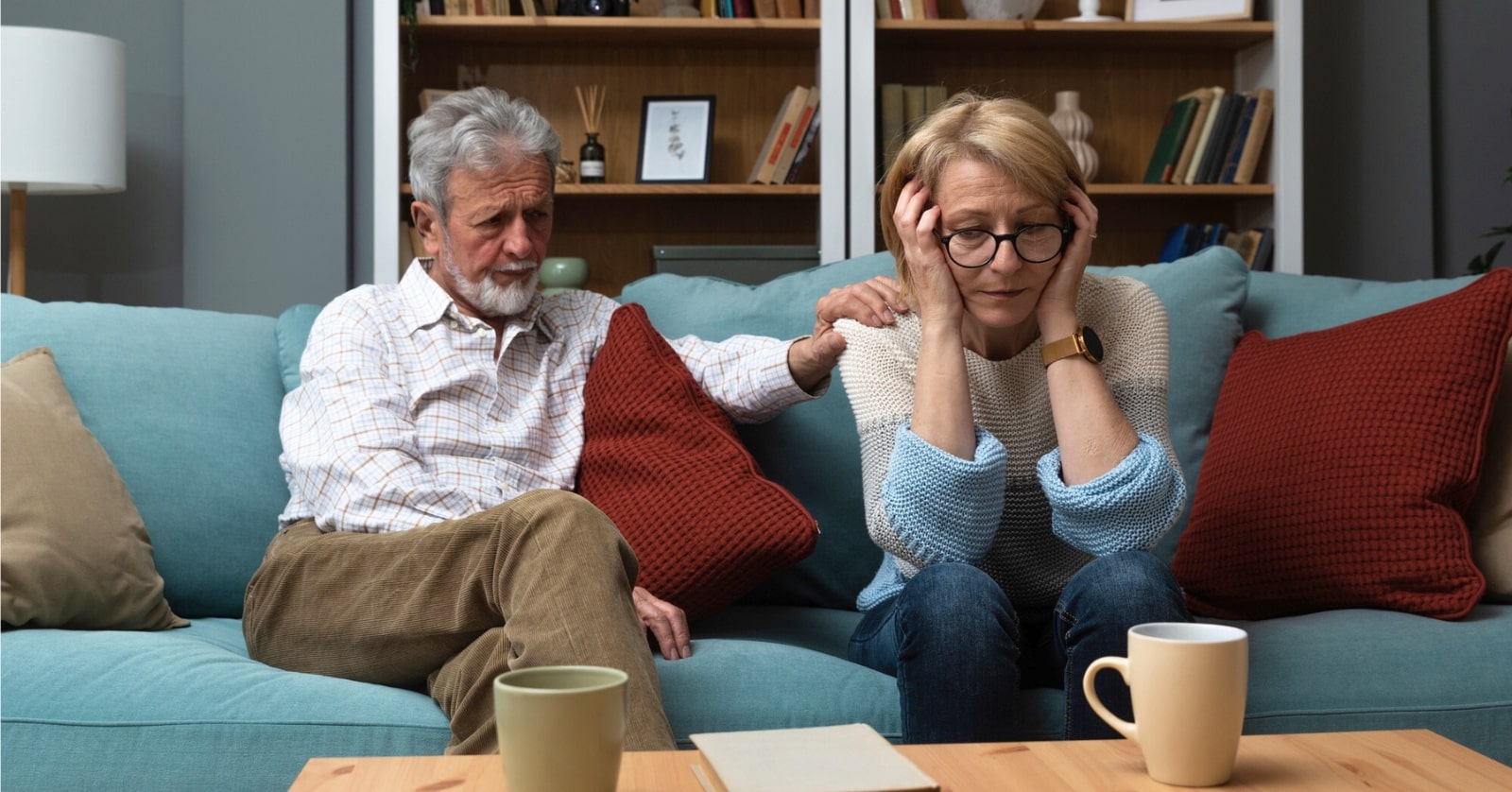 late middle aged couple looking unhappy sitting on the couch in their home after their children have moved out