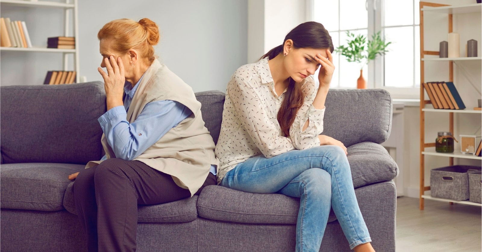 mother and grown daughter sitting on couch facing away from each other illustrating conflict