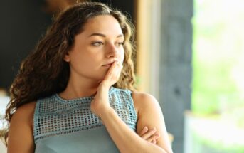pensive woman with hand on her cheek looking like she is overthinking