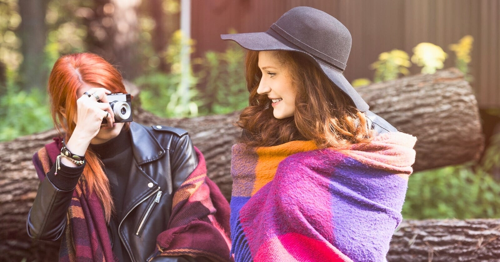 two female friends sitting next to each other, one taking a photo of the other - illustrating being loved by another